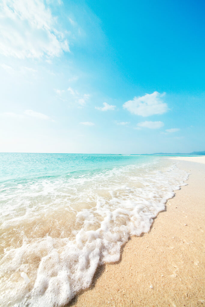 Verticale foto van een tropisch strand met wit zand, helderblauw water en zachte golven.